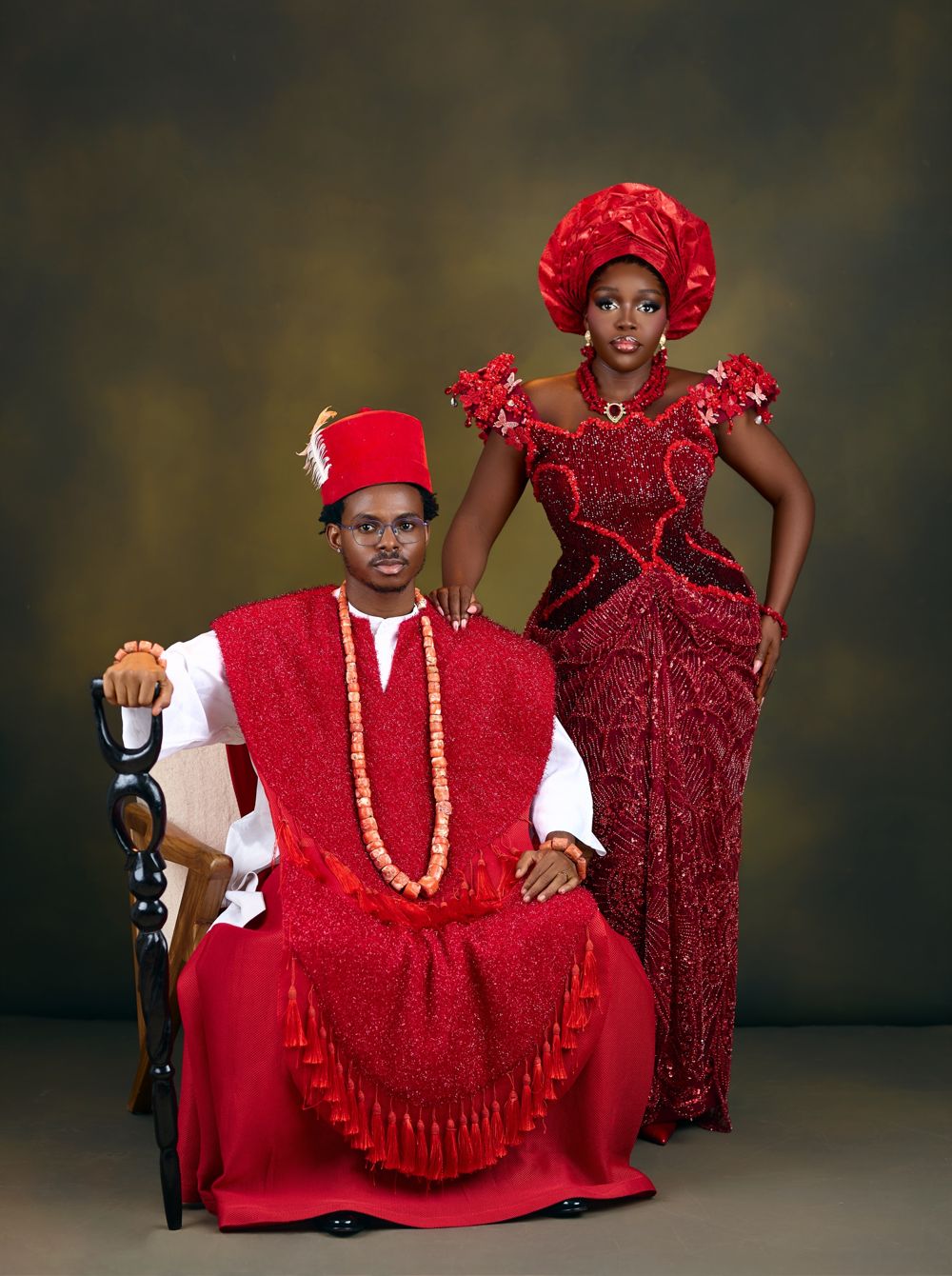 Makuo seated with his staff, Ogoo standing beside him in red Igbo traditional attire